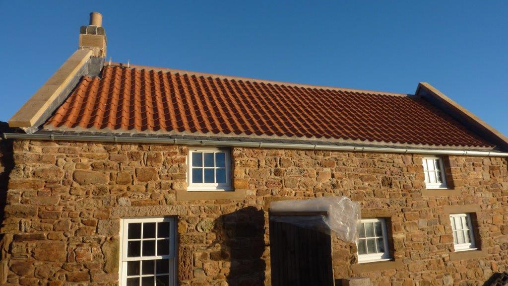Roofer repairing damaged roof tiles